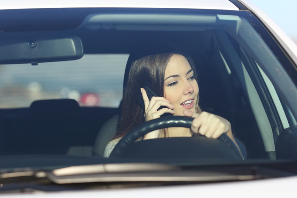 female on her phone violating distracted driving laws on the road