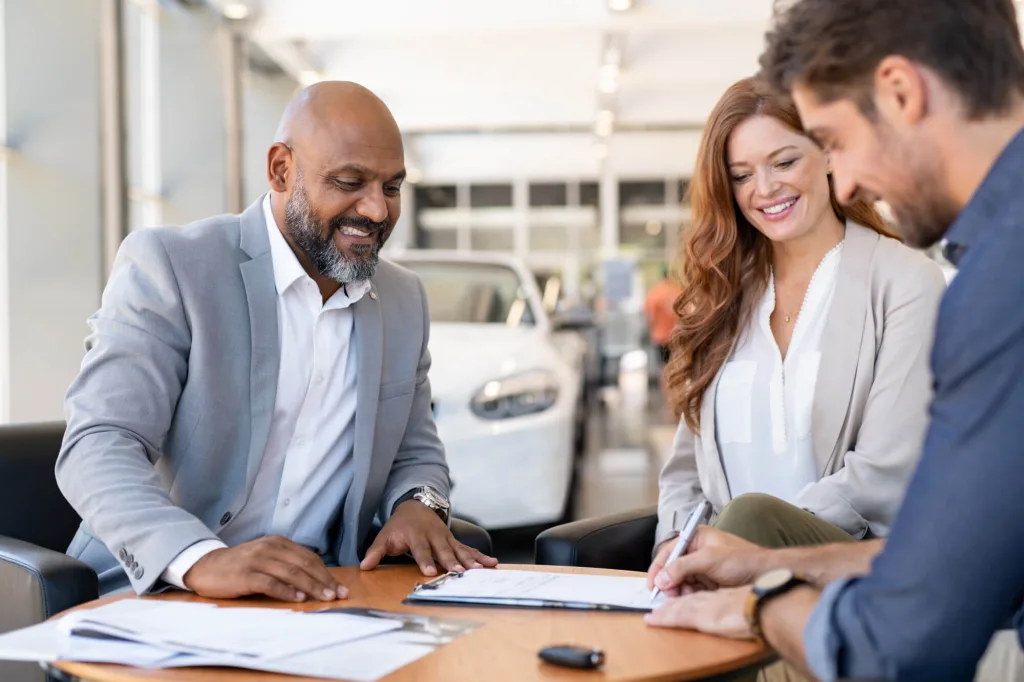 Couple signing the title transfer for new car
